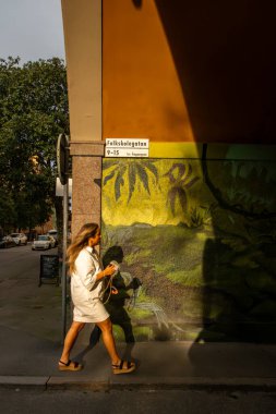 Stockholm, İsveç 4 Ağustos 2025. Sodermalm 'da genç bir kadın gün batımında Folkskolegatan' da yürüyor..