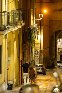 Cagliari, Sardinya, İtalya 10 Ağustos 2025 Tarihi şehir merkezinde Via Ospedale 'de yürüyen bir çift.