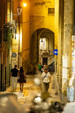 Cagliari, Sardinya, İtalya 10 Ağustos 2025 Tarihi şehir merkezinde Via Ospedale 'de yürüyen bir çift.