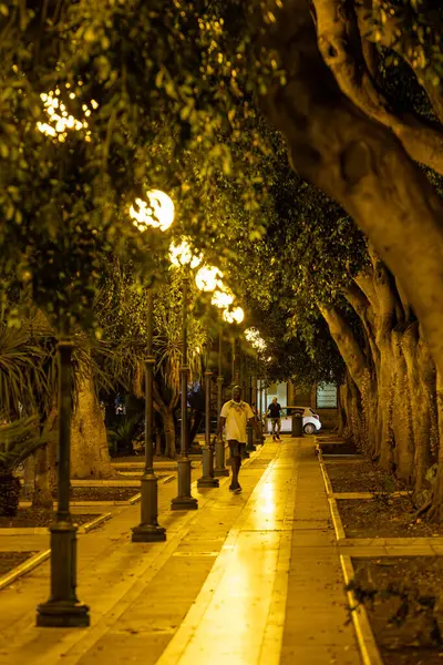 Cagliari, Sardinya, İtalya 9 Ağustos 2025 Bir adam tarihi şehir merkezinde Piazza del Carmine 'da gece yürüyor.