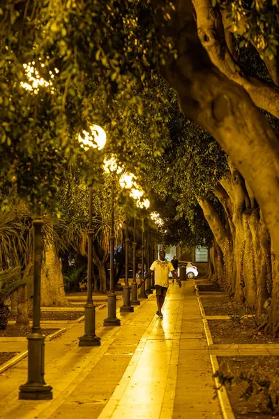 Cagliari, Sardinya, İtalya 9 Ağustos 2025 Bir adam tarihi şehir merkezinde Piazza del Carmine 'da gece yürüyor.