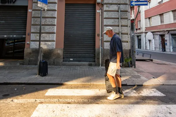 Cagliari, Sardinya, İtalya 15 Ağustos 2025 Bir adam tarihi şehir merkezinde tekerlekli çantayla yürüyor