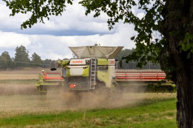 Enkoping, İsveç 26 Ağustos 2025 Kırsal kesimde bir hasat makinesi saman tarlasını kesiyor.