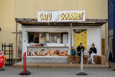 Stockholm, İsveç 28 Eylül 2025 Barkaby banliyösündeki bir büfede oturan genç bir aile ve İsveççe bir tabelada Gatu gurmesi veya sokak gurmesi diyor..