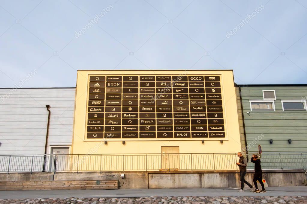 Stockholm, Sweden Sept 27, 2025 People walk past a huge sign with brand names at the Stockholm Quality Outlet outdoor mall in the Barkaby suburb.