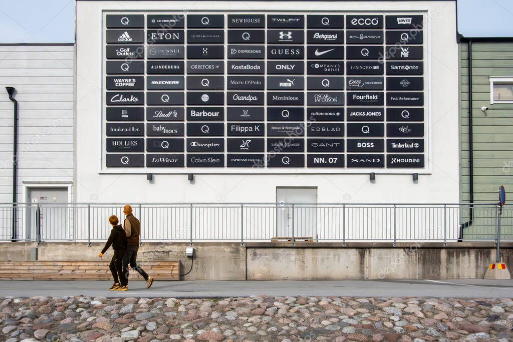 Stockholm, Sweden Sept 27, 2025 People walk past a huge sign with brand names at the Stockholm Quality Outlet outdoor mall in the Barkaby suburb.