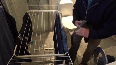 Stockholm, İsveç Bir adam ıslak çamaşırlarını kurutmak için askıya asıyor.  