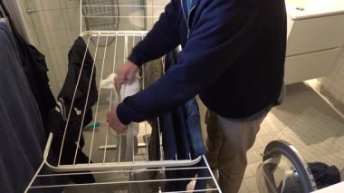 Stockholm, İsveç Bir adam ıslak çamaşırlarını kurutmak için askıya asıyor.  