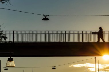 Stockholm, İsveç 1 Ekim 2025 Bir yaya gün batımında yaya köprüsünden geçiyor.
