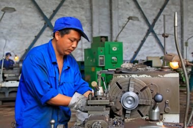 TANGSHAN ŞEHRİ - 20 Haziran 2014 'te Çin' in Hebei Eyaleti 'nde, Tangshan şehrinde, üretim atölyesinde makinede çalışan işçiler.