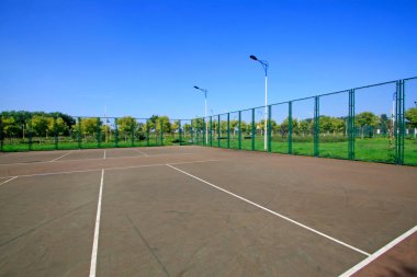 Tenis kortu çiti ve parkta sokak lambası.