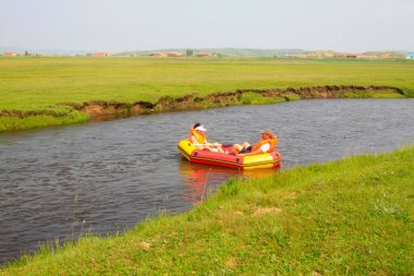 TULIGEN GRASSLAND - 20 Temmuz 2014: Ziyaretçiler Tuligen Nehri 'nde 20 Temmuz 2014 tarihinde şişme sandal sürüklenmesi, Xilin gol ligi, Moğolistan özerk bölgesi, Çin.