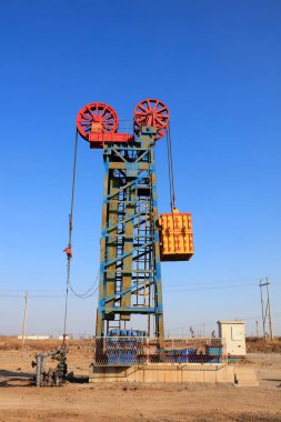 Petrol sahasında mavi gökyüzünün altında kule tipi pompalama ünitesi