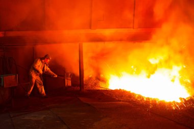 Demir fabrikası fırın deliğinde erimiş demir fışkırtıyor, fotoğrafa yakın çekim yapıyor.