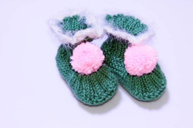 Beyaz arkaplanda yün örülmüş çocuk ayakkabıları, fotoğrafın yakın çekimi