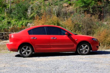 Kırmızı araba dağ ülkesinde duruyor, fotoğrafa yakın çekim.