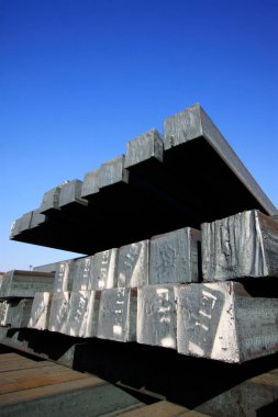 Mavi gökyüzünün altında çelik külçeler, fotoğrafa yakın çekim.