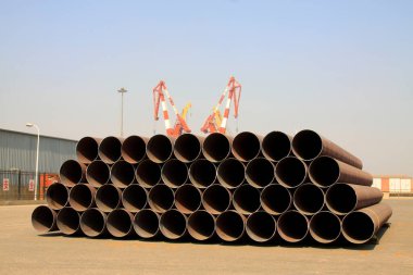 Çelik boru ve vinç yığınları, fotoğrafın yakın çekimi.