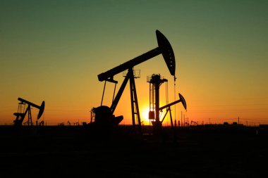 Petrol sahasında batan güneşin altında dengeli pompalama ünitesi