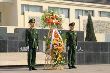 LUANNAN COUNTY - 22 Mart 2014 'te Pan Dai köyü katliam anıtı dış binasında çiçek sepeti taşıyan silahlı polis askerleri, Luannan County, Hebei, Chin