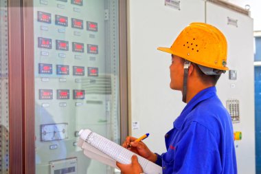 TANGSHAN - 18 Haziran 2014, Tangshan City, Hebei Eyaleti, Chin 'de bulunan demir ve çelik bir kooperatifte, kontrol odasındaki teknik personel okuma kayıtları.