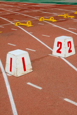 Seri numarası işaretlenmiş ve orta okuldaki bir spor sahasındaki kırmızı plastik pistte donanım çalıştırılıyor.