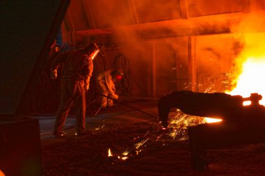 Demir fabrikası fırın deliğinde erimiş demir fışkırtıyor, fotoğrafa yakın çekim yapıyor.