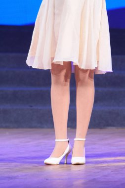 Sahnede yüksek topuklu ayakkabı giyen kadın bacakları.
