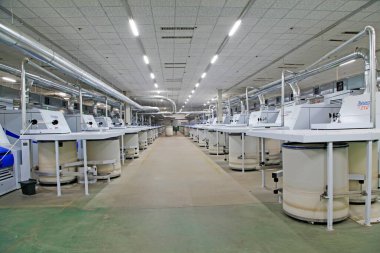 Fabrikada dönen makine parçaları ve beyaz plastik kovalar, yakın çekim