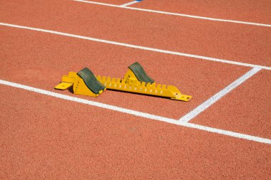 Sarı başlangıç bloğu ve sporcular, fotoğrafa yakın çekim