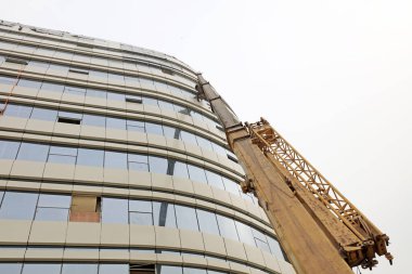 Bir inşaat alanında vinç kolu ve cam perde duvarı