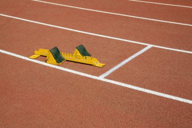 Sarı başlangıç bloğu ve sporcular, fotoğrafa yakın çekim