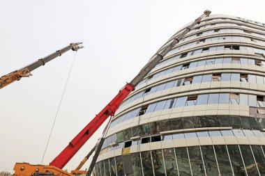 Bir inşaat alanında vinç kolu ve cam perde duvarı