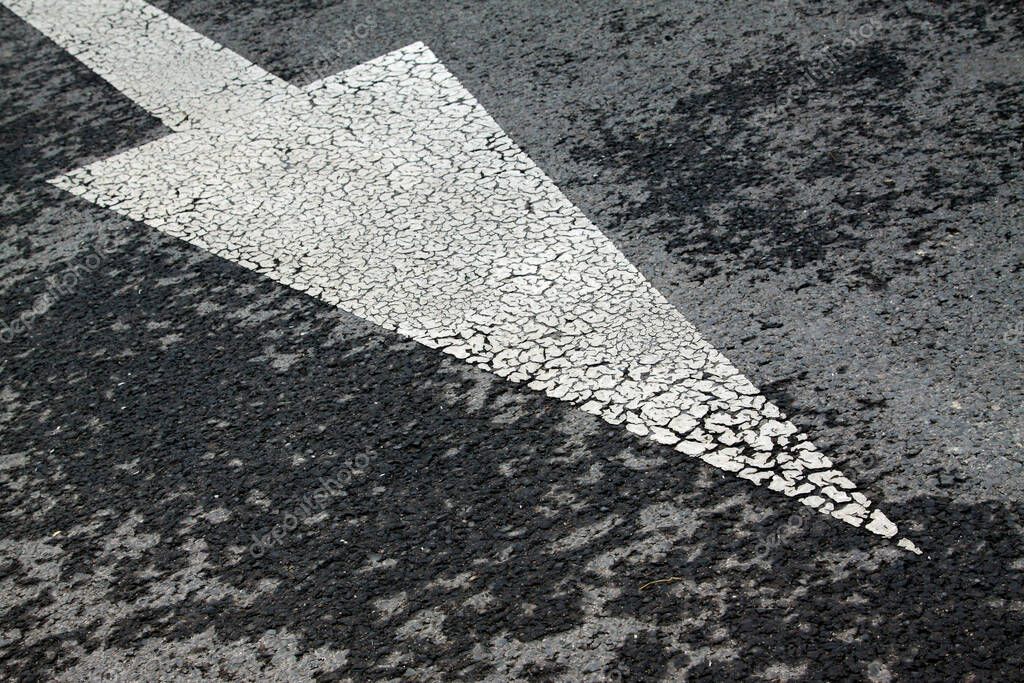 White arrow symbol on asphalt road, closeup of photo