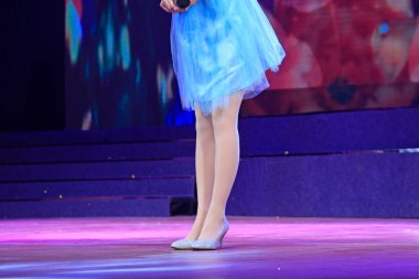 Sahnede mavi etek, filar çorap giymiş yüksek topuklu ayakkabılar giyen bayan. 