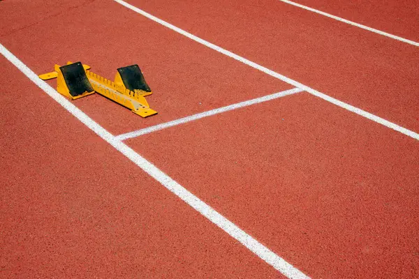 Sarı başlangıç bloğu ve sporcular, fotoğrafa yakın çekim