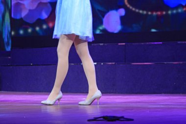 Sahnede mavi etek, filar çorap giymiş yüksek topuklu ayakkabılar giyen bayan. 