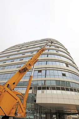 Bir inşaat alanında vinç kolu ve cam perde duvarı