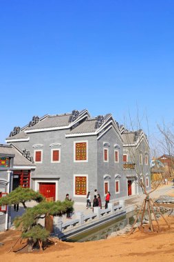 İnsanlar açık mavi gökyüzü altında geleneksel gri binaları ziyaret ediyorlar