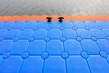 Turuncu kenarları ve suyu olan mavi yüzen rıhtım bölümleri