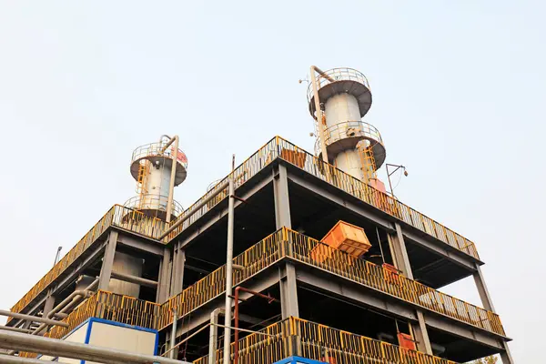 İki uzun bacası ve iskelesi olan sanayi binası.