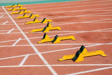 Sarı başlangıç bloğu ve sporcular, fotoğrafa yakın çekim