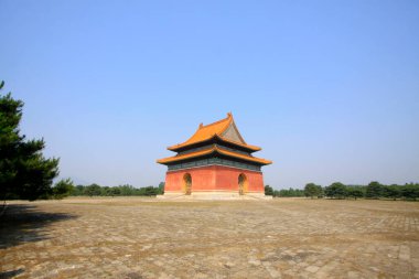 Geleneksel bina açık mavi gökyüzü altında ağaçlarla çevrili.
