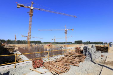 Turnalar, malzemeler ve açık mavi gökyüzünün yer aldığı inşaat alanı