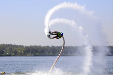 Suyun üstünde uçan kişi sıçrama yaratıyor.