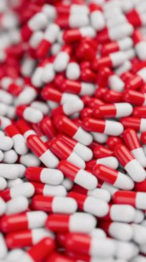 Beyaz ve kırmızı hapların yakınlaştırılması ve yavaş çekimde sığ DOF ile karıştırılması. İlaçlar, haplar, haplar, ilaç konsepti. 3D canlandırma canlandırması. Dikey video.