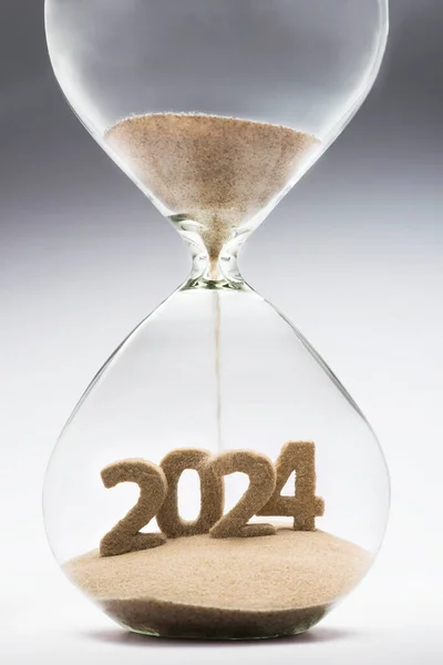 2024年新年的概念 沙漏落沙的形状为2024年 图库照片