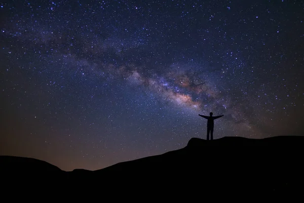 天の川 星と山の上に立って幸せな人々 のシルエットと夜の空のある風景 長い露出写真は ストック画像