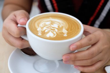 Kahve dükkanında elinde bir fincan sıcak kahve tutan bir kadın.