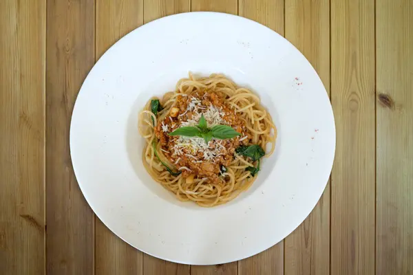 spaghetti with meat sauce and basil on wooden